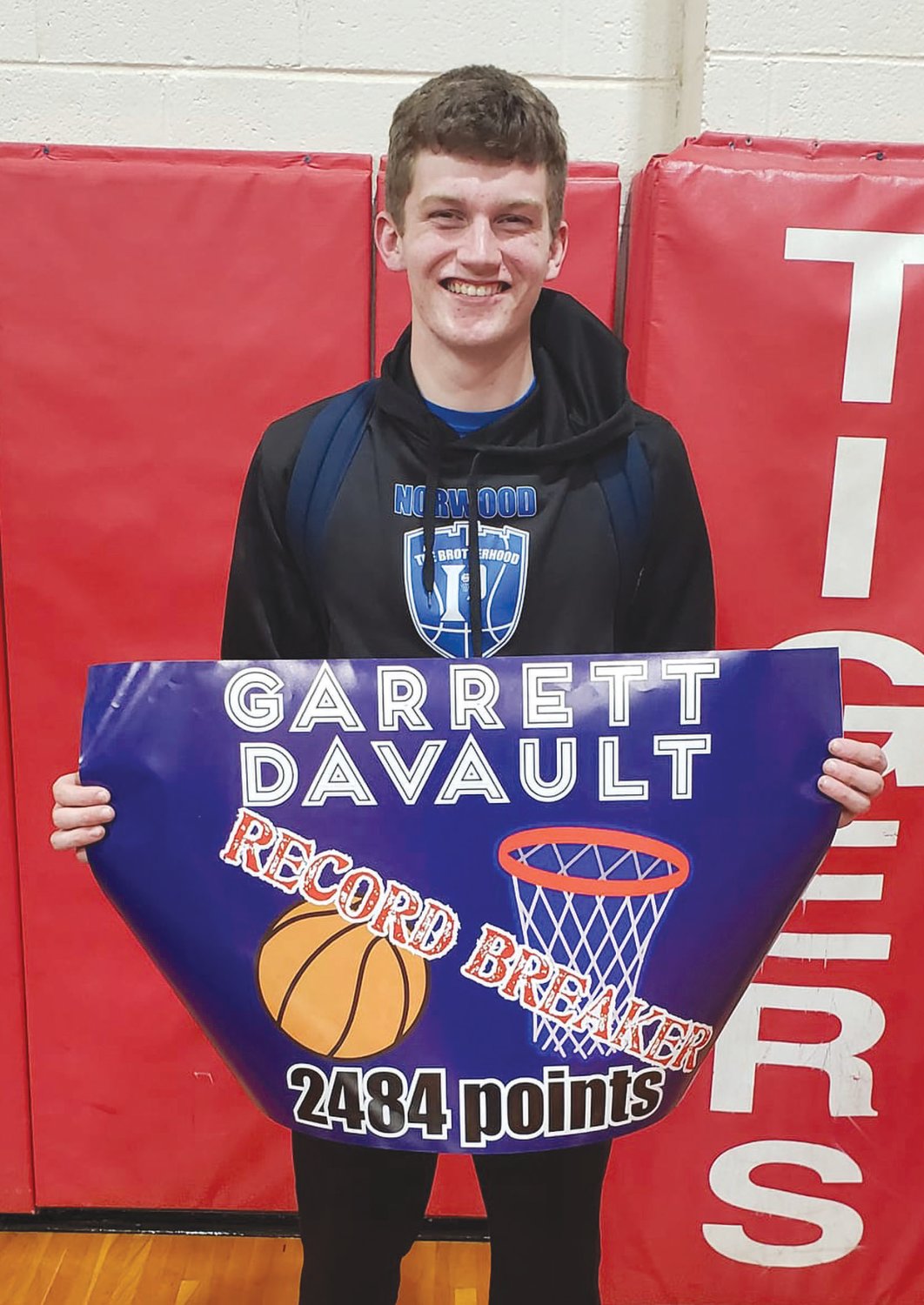 Norwood’s Garrett Davault holds up a sign in Hurley’s gym after breaking the career scoring record for the Pirates’ program.